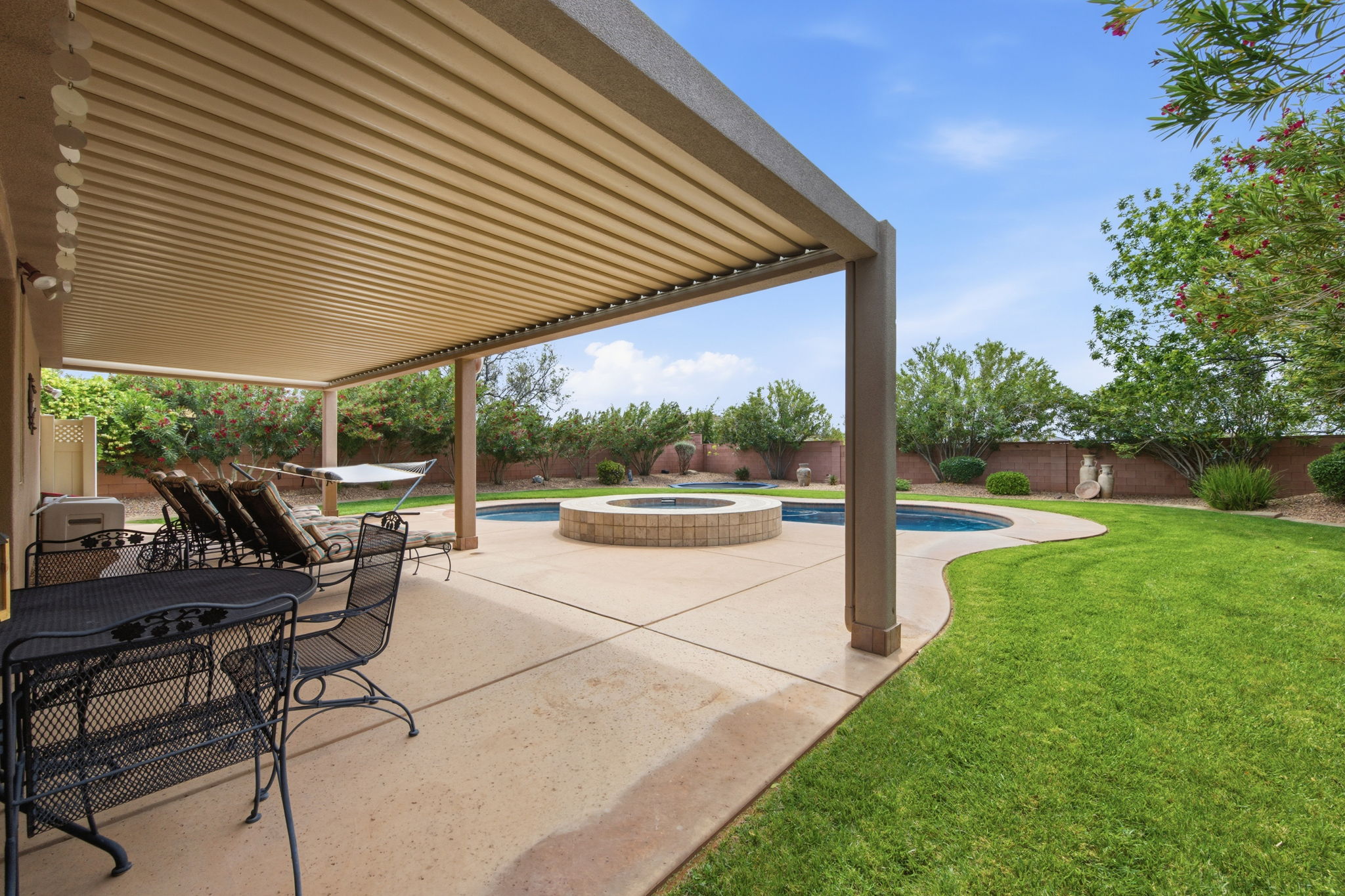 Fenced backyard featuring a patio area, a pool with connected hot tub, and a pergola