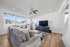 Living room with plenty of natural light, a textured ceiling, light wood-type flooring, a ceiling fan, and recessed lighting
