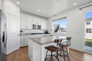 Kitchen featuring white cabinetry, an island with sink, light wood-type flooring, stainless steel appliances, and recessed lighting