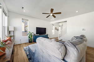 Living room with a ceiling fan, a textured ceiling, light wood-style flooring, and recessed lighting