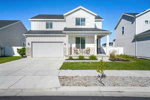 Modern farmhouse featuring board and batten siding, a porch, an attached garage, driveway, and a shingled roof