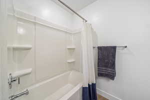 Bathroom with shower / bath combination with curtain and wood finished floors