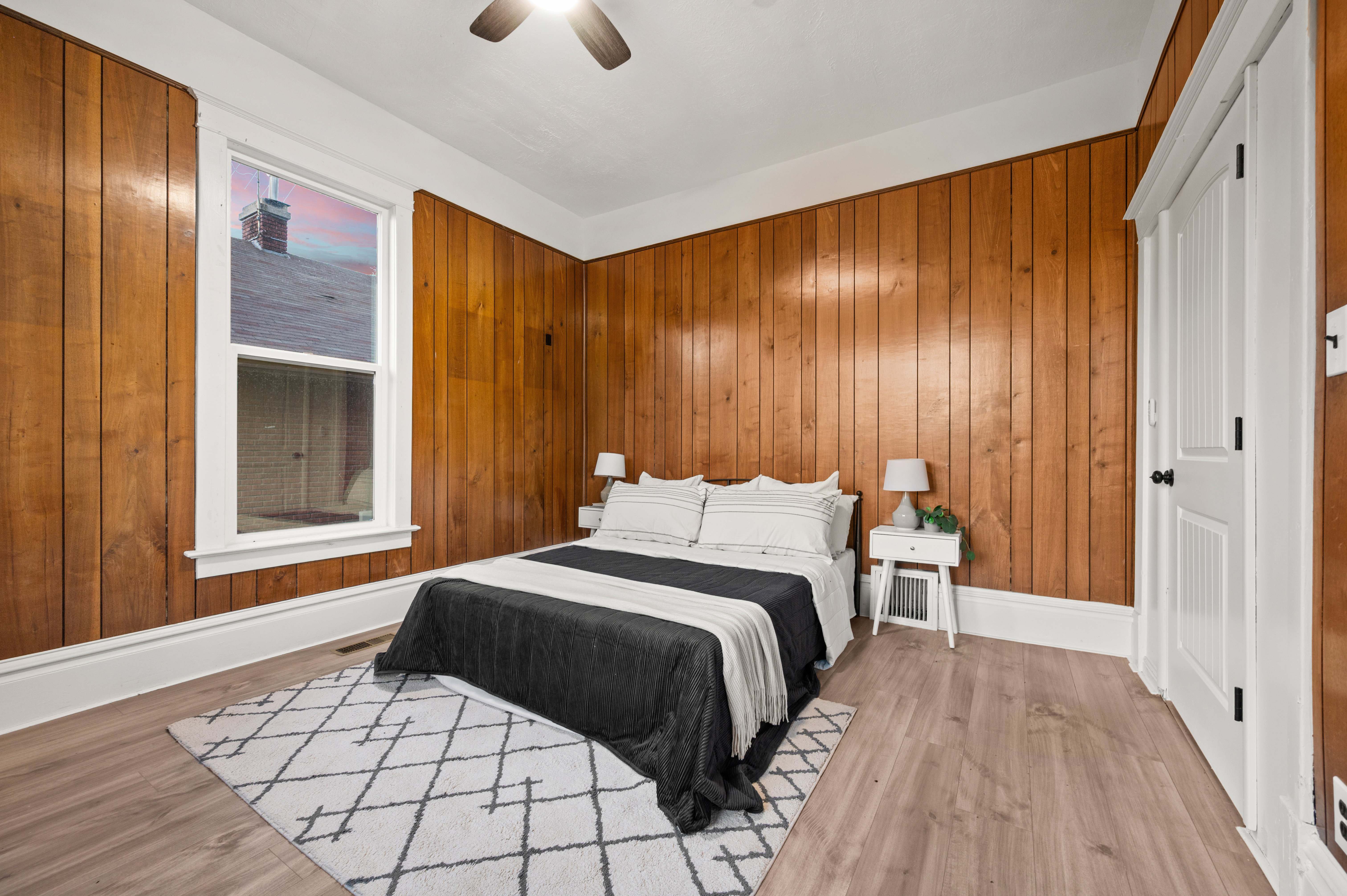 Bedroom featuring wood-panel accent walls and light wood-finish flooring