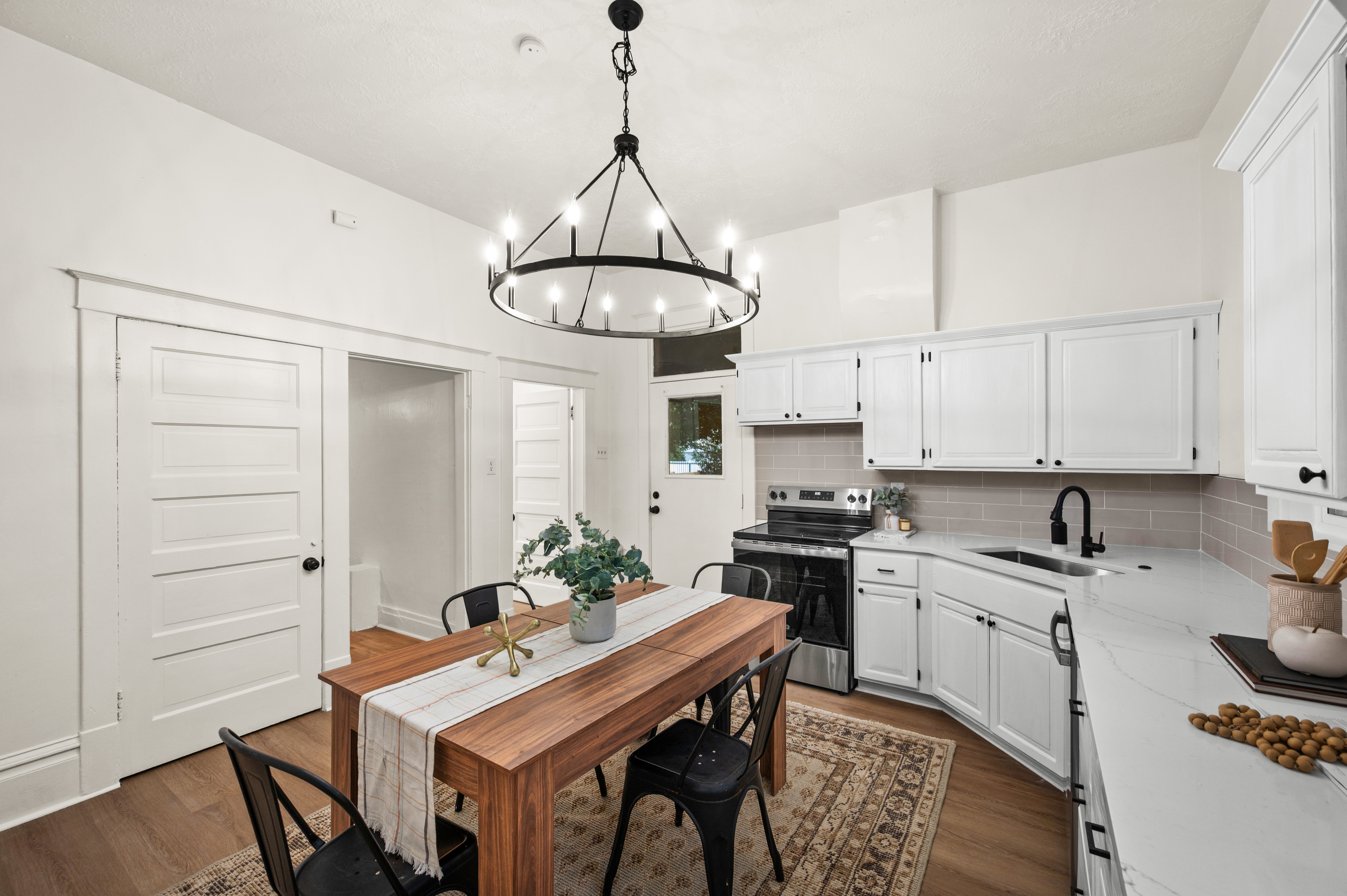 Open-concept kitchen and dining area featuring white cabinetry, a light gray subway tile backsplash, and light-colored countertops