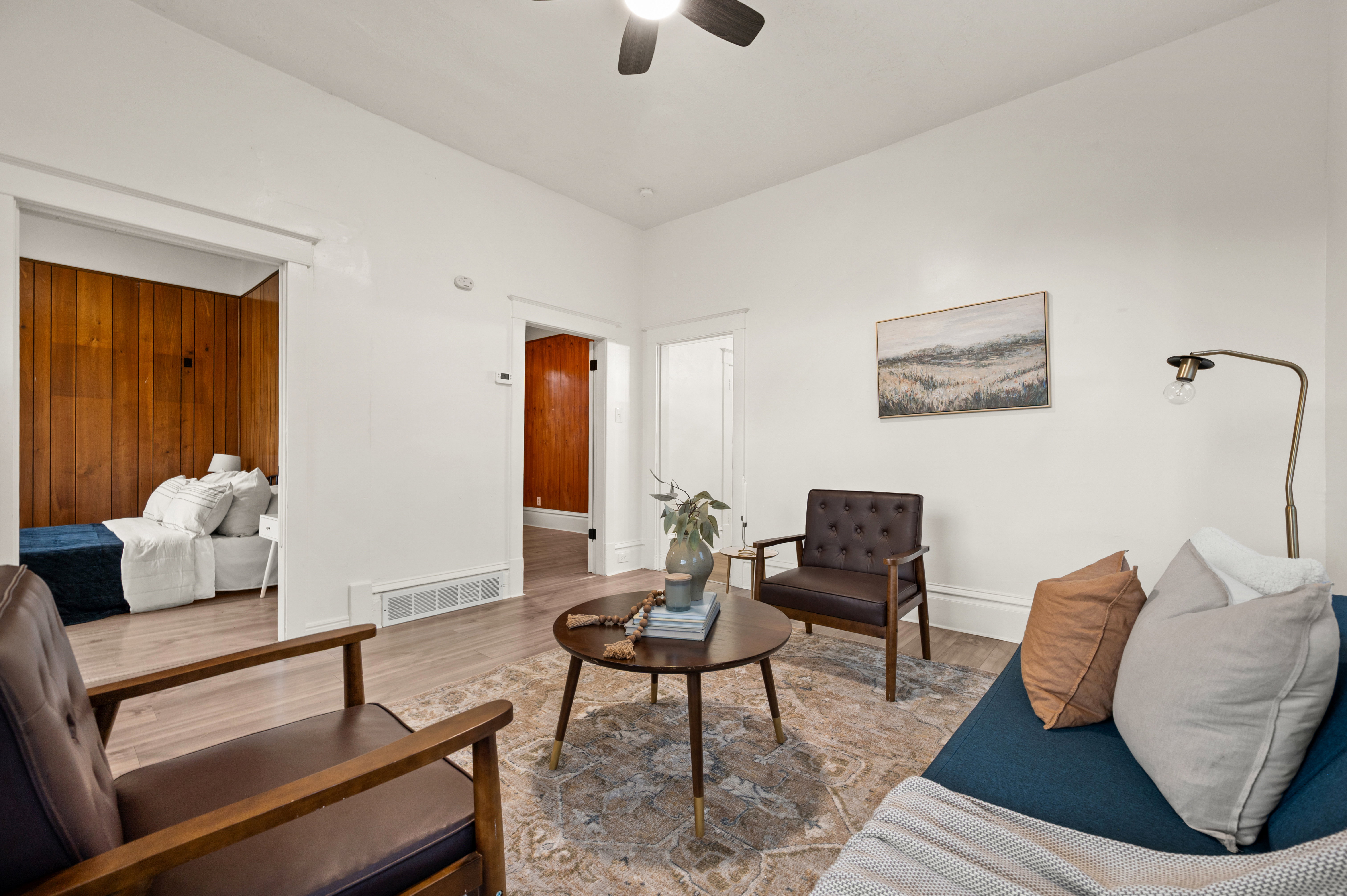 Spacious living area featuring light wood-finish flooring and a ceiling fan