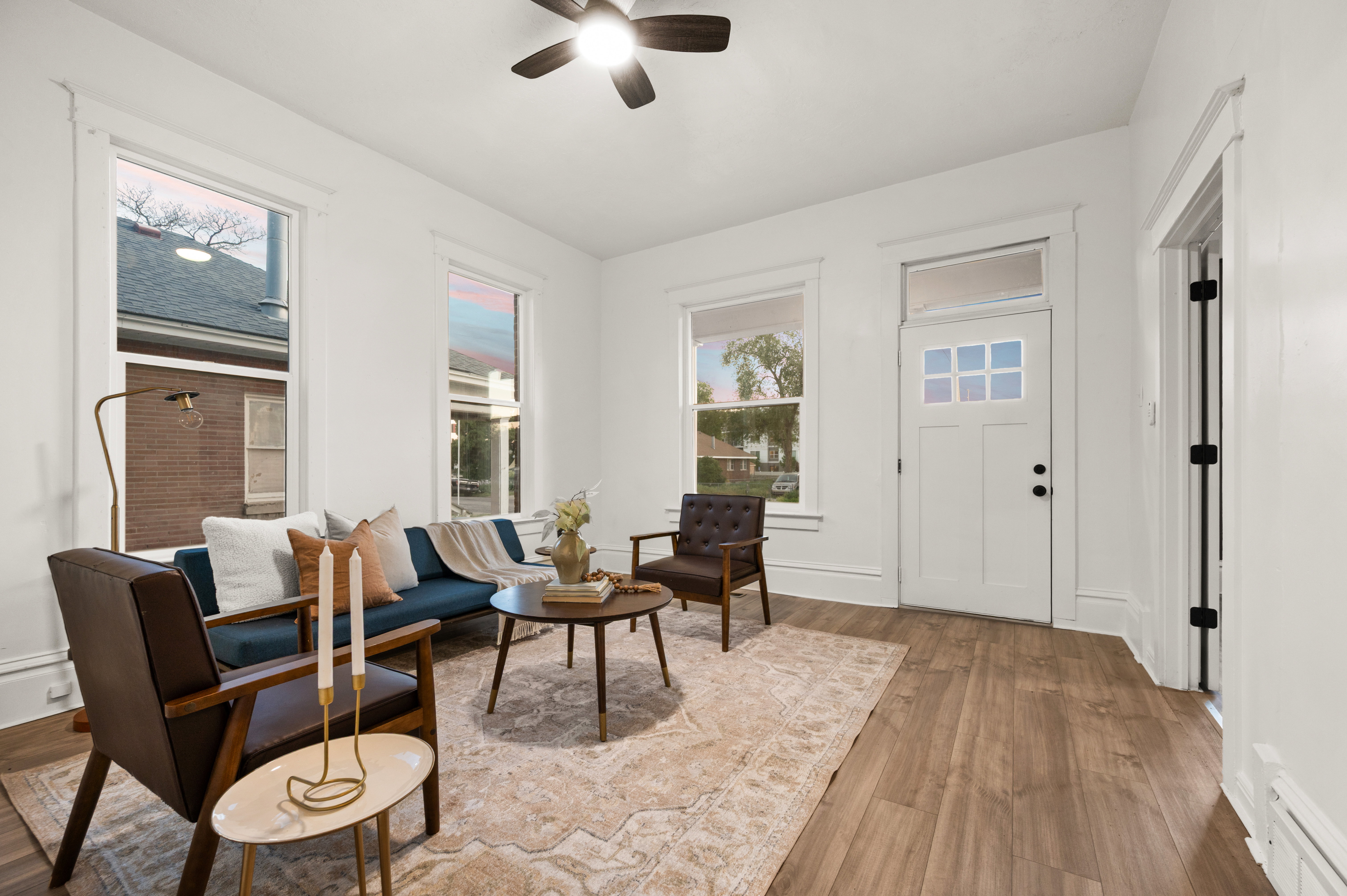Living space with wood-finish flooring, white walls, and a ceiling fan