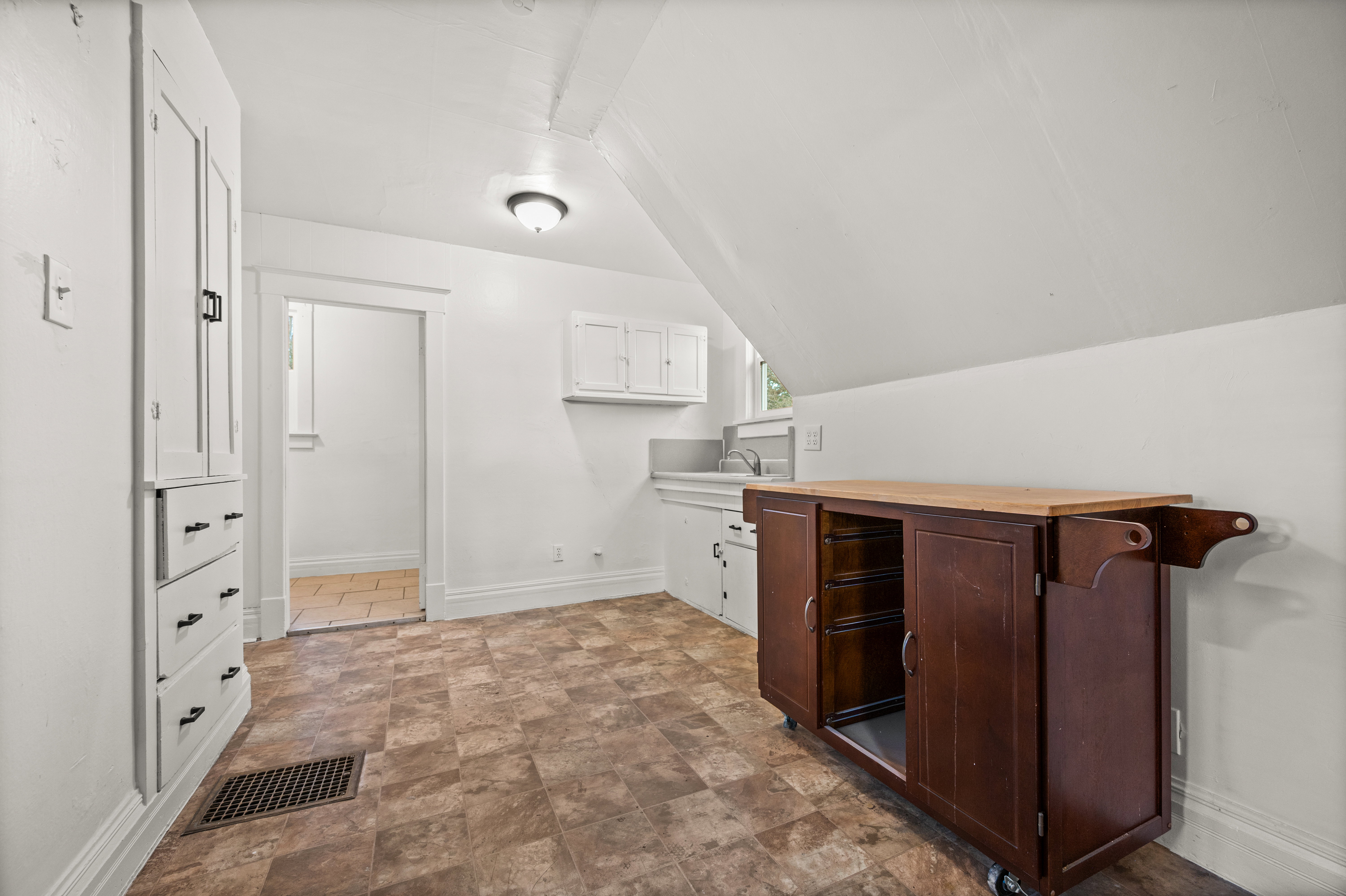 Bar area featuring stone finish flooring, white cabinetry, vaulted ceiling, and butcher block countertops