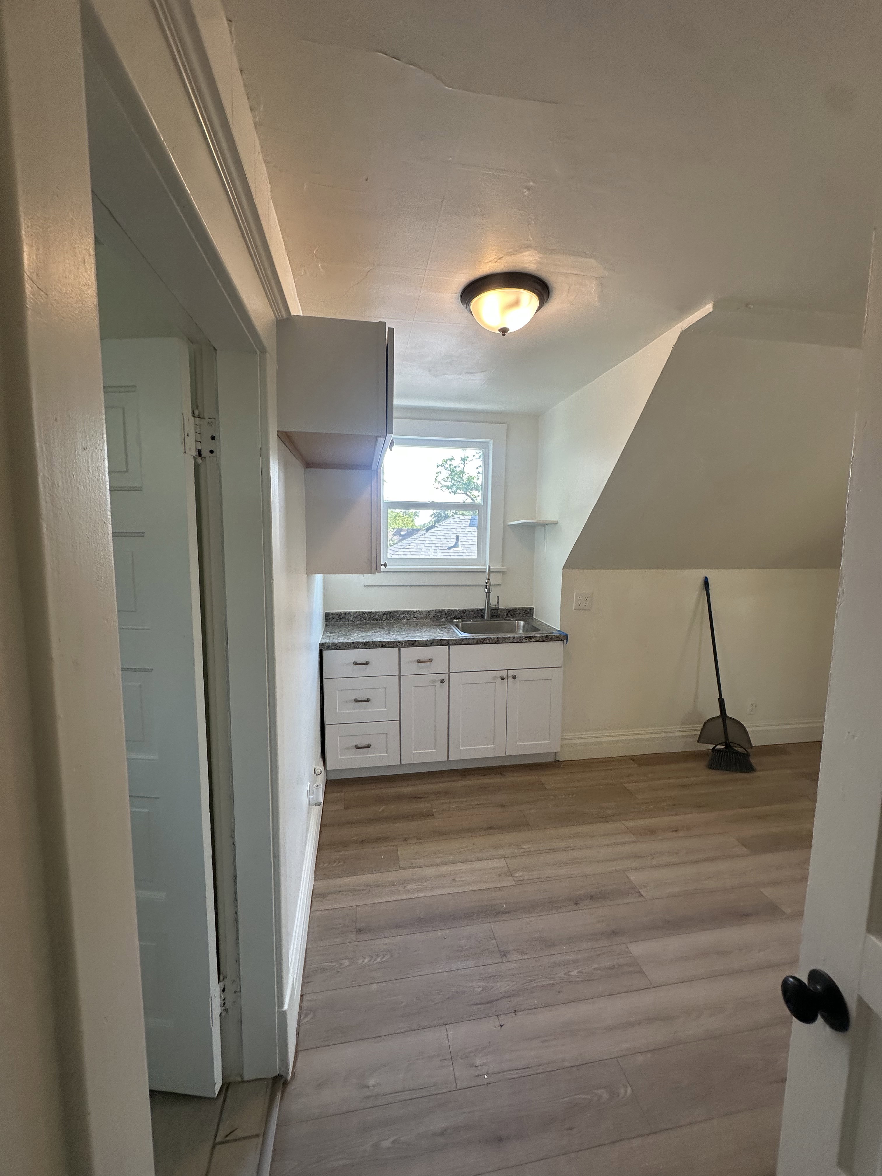 Compact kitchenette featuring white cabinetry, a single basin sink, and a granite-look countertop