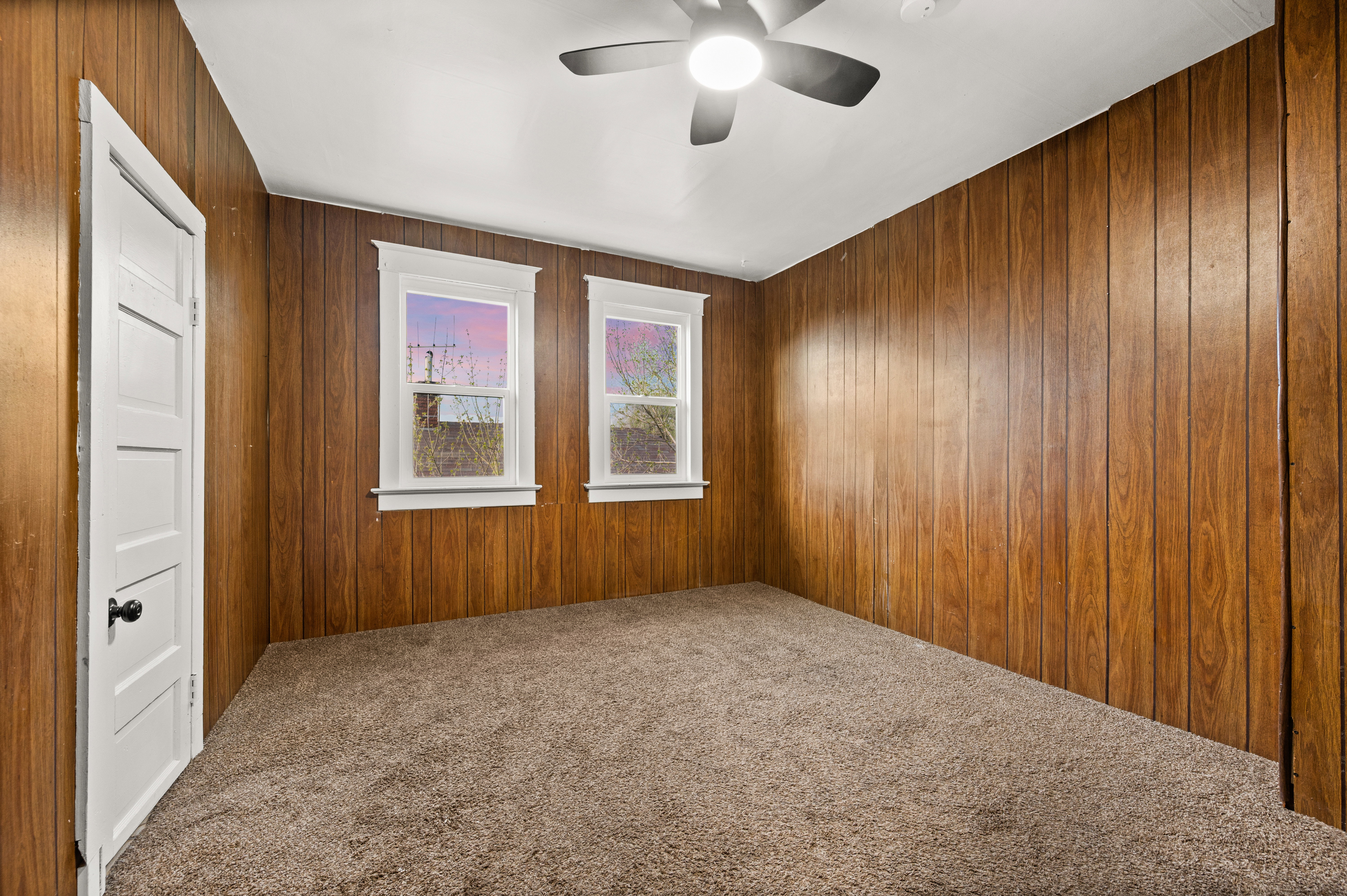Unfurnished room with carpet, a ceiling fan, and wood walls