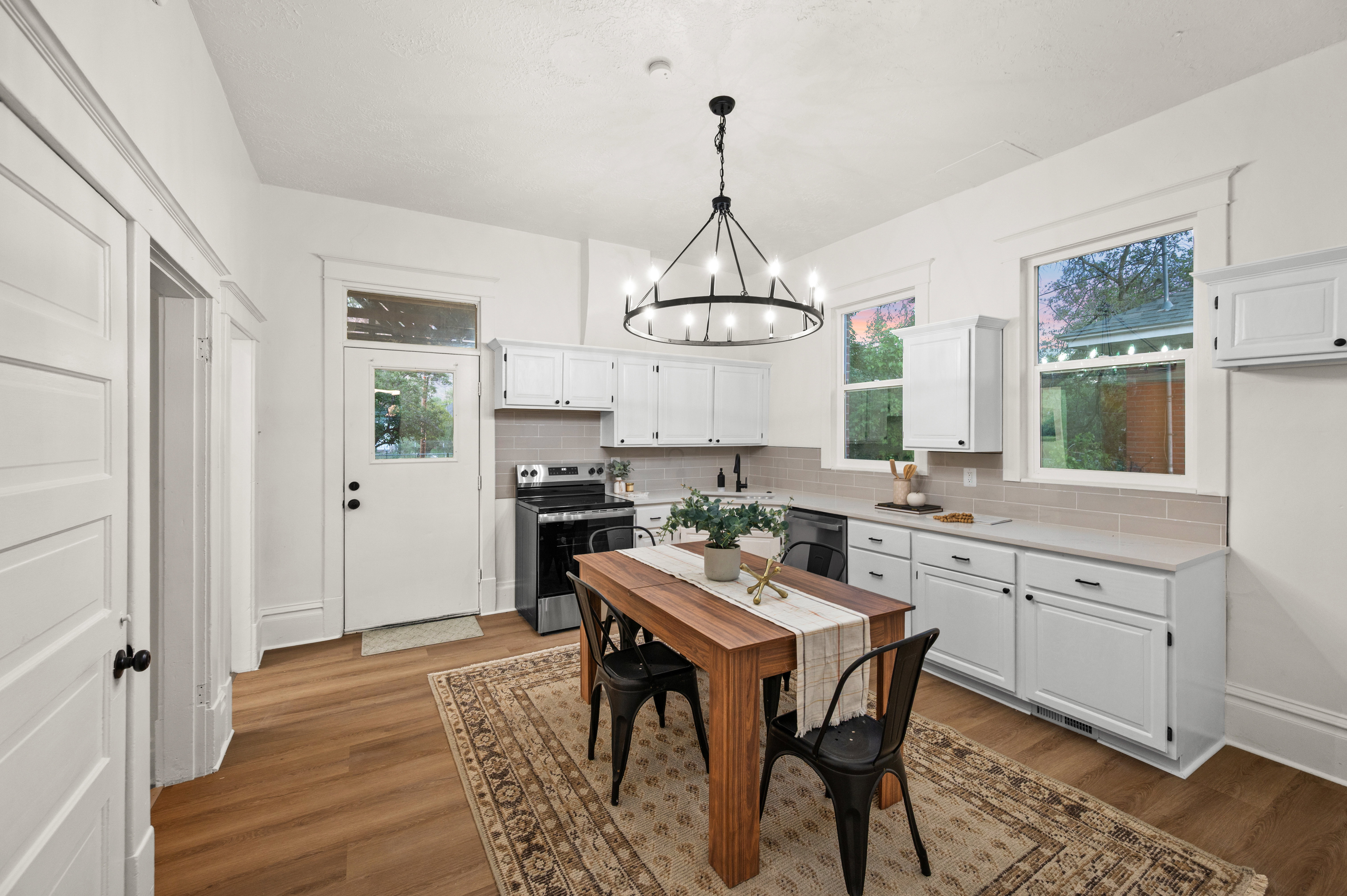 Bright kitchen featuring white cabinetry, light wood-finish flooring, a tile backsplash, and a black appliance suite