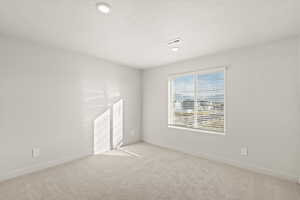Empty room with light colored carpet, a textured ceiling, and recessed lighting