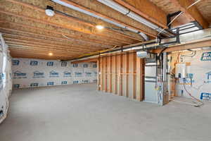 Unfinished basement featuring heating unit and tankless water heater