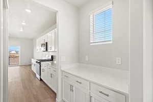Kitchen featuring stainless steel appliances, white cabinetry, light wood-style floors, light stone counters, and recessed lighting