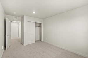 Unfurnished bedroom with light colored carpet and a closet
