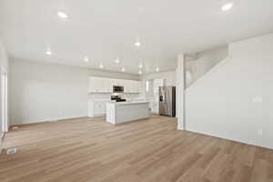 Kitchen featuring open floor plan, stainless steel appliances, light countertops, light wood-style floors, and recessed lighting