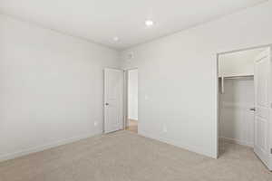 Unfurnished bedroom with light colored carpet and a walk in closet