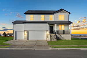 **DISCLAIMER** Grass not included. View of front of house with covered porch, a front yard, driveway, board and batten siding, and an attached garage