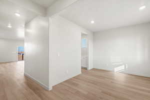 Empty room with recessed lighting, beam ceiling, and light wood-style floors