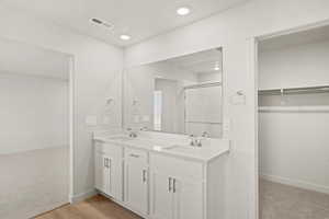 Bathroom with double vanity, a spacious closet, a stall shower, light carpet, and recessed lighting