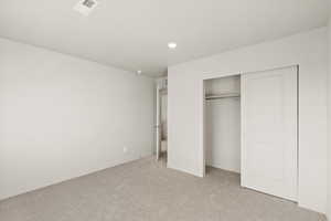 Unfurnished bedroom featuring light carpet and a closet