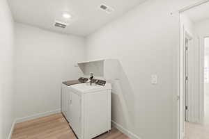 Laundry area with light wood finished floors and independent washer and dryer