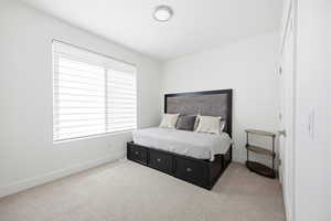 Bedroom with light colored carpet and baseboards