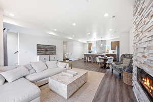 Living room featuring a stone fireplace, wood finished floors, and recessed lighting
