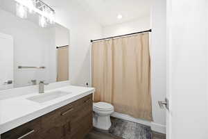 Bathroom featuring vanity, dark wood-style flooring, shower / tub combo, and recessed lighting