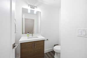 Half bathroom with vanity and dark wood-style flooring