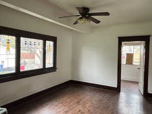 Empty room with ornamental molding, dark wood-type flooring, and a ceiling fan