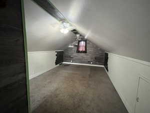 Additional living space featuring a ceiling fan and dark colored carpet