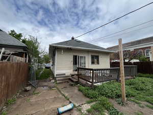 Back of property with a wooden deck, a chimney, and a shingled roof
