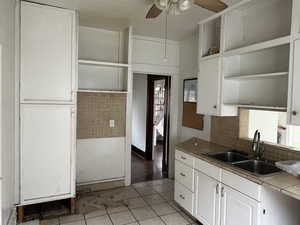 Kitchen with tile countertops, open shelves, white cabinets, and a ceiling fan