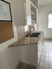Kitchen featuring tile counters, tasteful backsplash, wood walls, white cabinets, and light tile patterned flooring