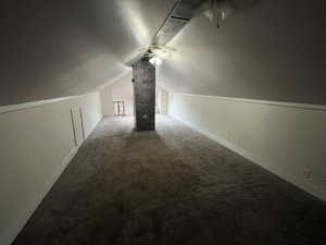 Additional living space featuring dark colored carpet and a ceiling fan
