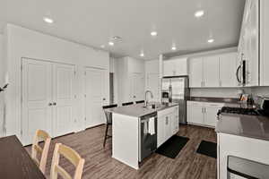 Kitchen with white cabinets, a breakfast bar, dark wood-style floors, and recessed lighting