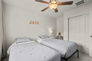 Carpeted bedroom with a ceiling fan and a closet