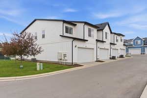 View of side of property featuring a lawn, an attached garage, a residential view, and board and batten siding