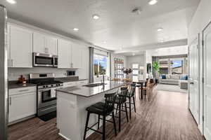 Kitchen with stainless steel appliances, white cabinetry, a kitchen bar, recessed lighting, and a kitchen island with sink