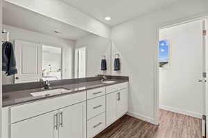 Bathroom featuring double vanity, dark wood-style floors, and recessed lighting