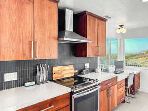 Kitchen featuring stainless steel range with electric stovetop, tasteful backsplash, a textured ceiling, light stone countertops, and wood finish cabinetry