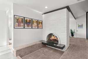 Unfurnished living room featuring a fireplace, light carpet, recessed lighting, and lofted ceiling