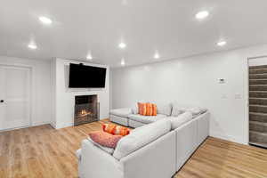Living area with light wood-style floors, a tile fireplace, and recessed lighting