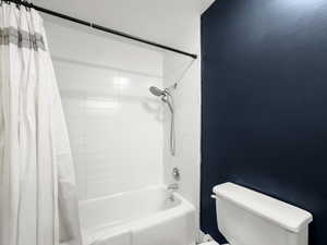 Full bath with toilet and shower / bathtub combination with curtain