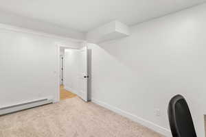 Spare room featuring baseboard heating and light carpet