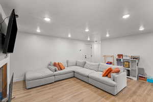 Living area featuring light wood finished floors, a textured ceiling, recessed lighting, and a fireplace