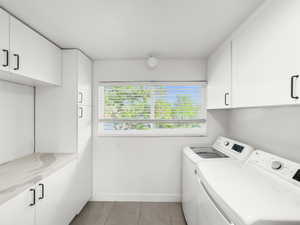Laundry area featuring cabinet space, washing machine and clothes dryer, and light tile patterned floors