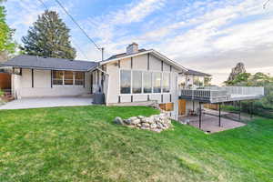 Rear view of property with stucco siding, a patio, a yard, a chimney, and roof with shingles