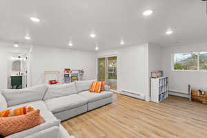 Living area featuring light wood finished floors, baseboard heating, and recessed lighting