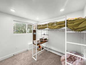 Carpeted bedroom with baseboard heating and recessed lighting